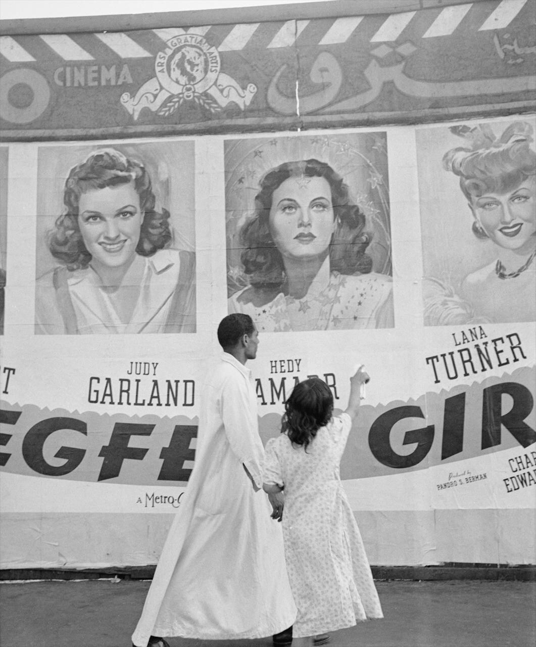 A man and his daughter pass posters in Cairo, Egypt, 1942