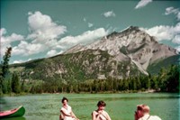 A man photographs two women in a canoe on the Bow River