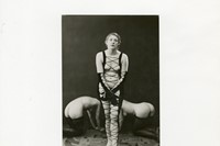 Woman in fetish clothing standing in front of two kneeling w