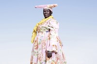 Herero woman in pink dress with yellow scarf