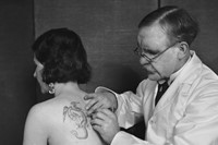 Mr Burchett tattooing a woman&#39;s back, 1931