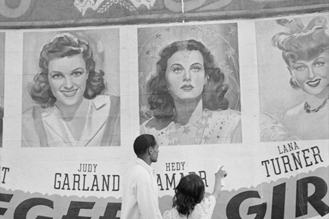A man and his daughter pass posters in Cairo, Egypt, 1942