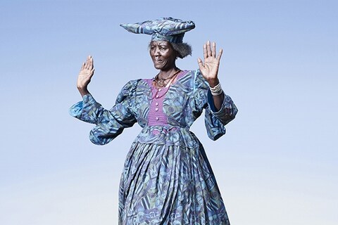 Herero woman in blue dress in cow dance pose