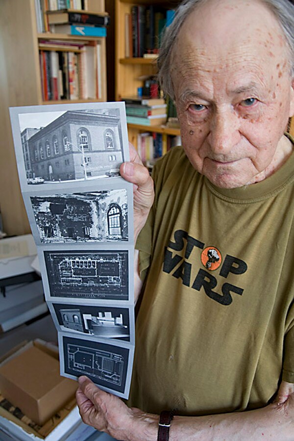Jonas holding up a postcard series of the derelict building 