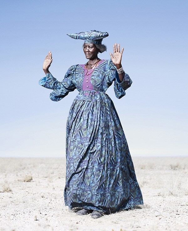 Herero woman in blue dress in cow dance pose