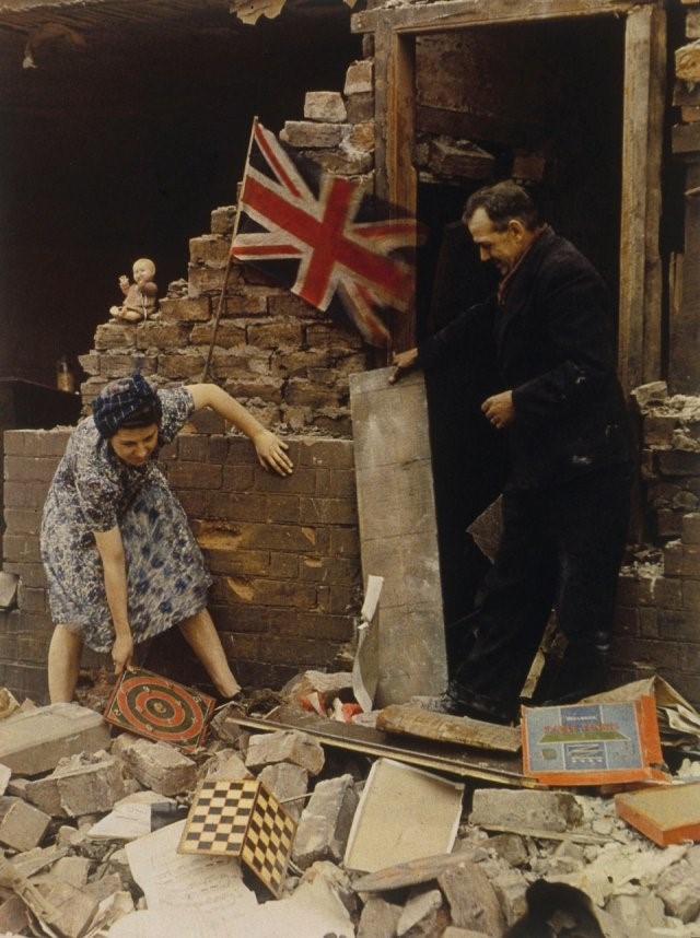 A woman saves a board game from bomb wreckage, c. 1940-1945