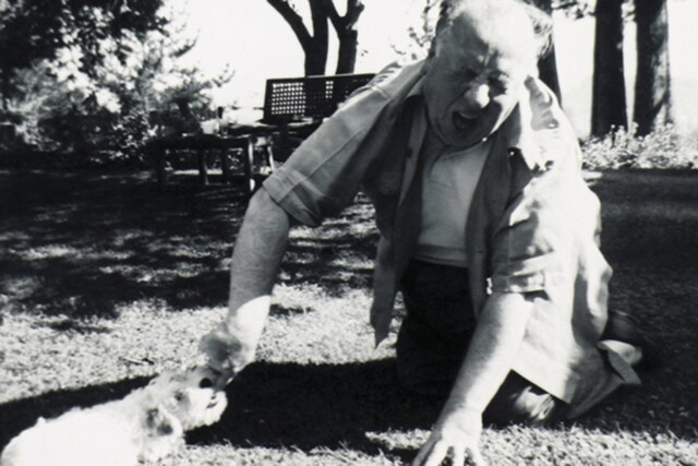 Alfred Hitchcock plays with one of his Sealyham Terriers. Ho
