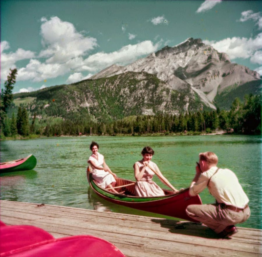 A man photographs two women in a canoe on the Bow River