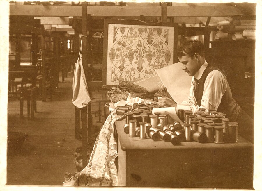 Reginald Warner inspecting silk thread. Note-flora