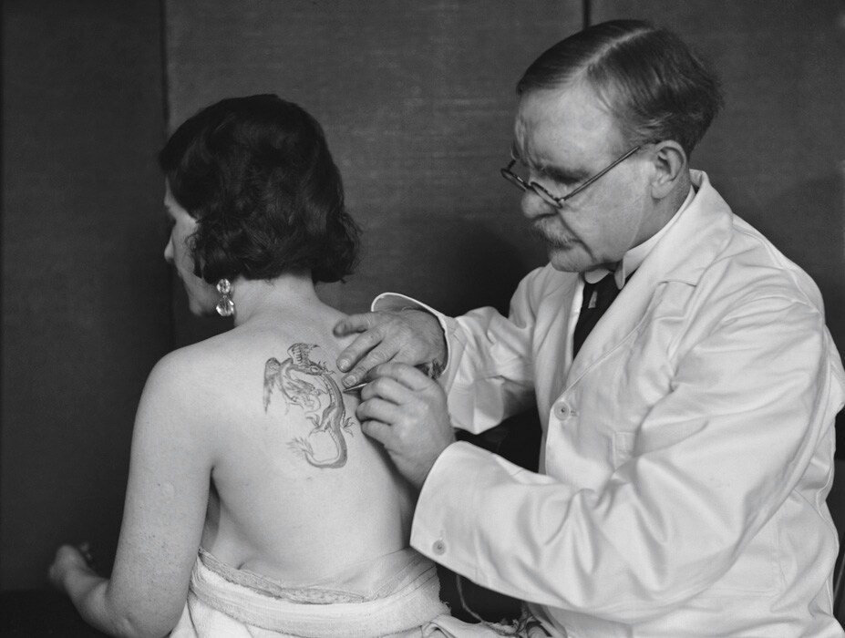 Mr Burchett tattooing a woman&#39;s back, 1931